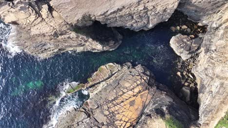 Birdseye-Aerial-View-of-Sunny-Coastline-of-Scotland-UK,-Steep-Cliffs,-Blue-Sea-and-Green-Pastures-60fps