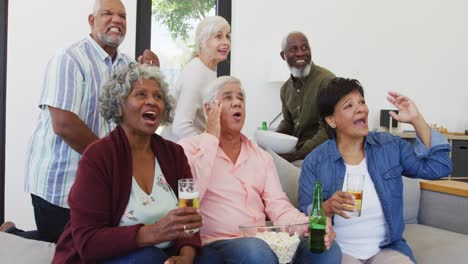 personas mayores felices y diversas viendo televisión con cerveza en el hogar de ancianos