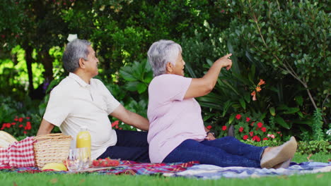 video of happy biracial senior couple having picnic in garden