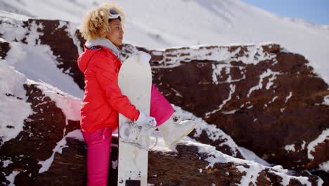 Skier-leaning-on-rocks-with-snowboard