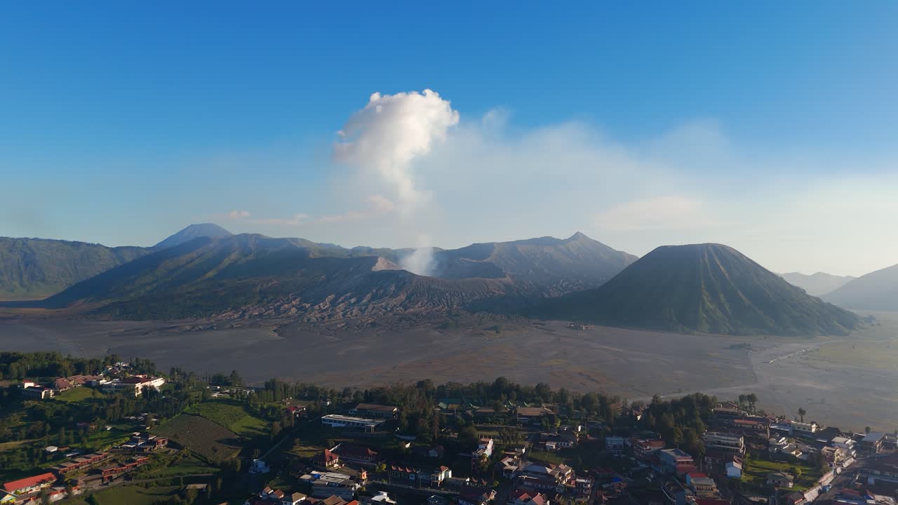 Il villaggio di Cemoro Lawang si affaccia sul Monte Bromo mentre si alza il fumo, Java orientale, ripresa aerea in allontanamento