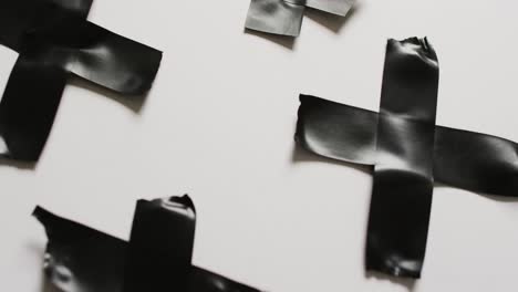 Video-of-close-up-of-black-tape-forming-crosses-on-white-background