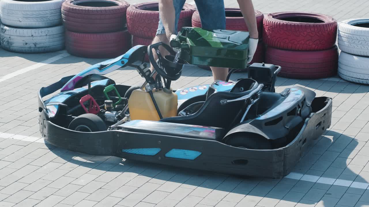 The mechanic go kart racing service pours fuel into the tank