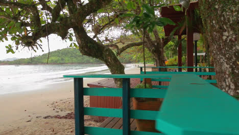 vista en primera persona de una casa de madera rodeada por la playa y árboles tropicales