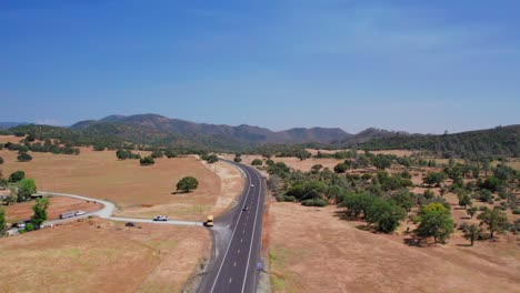 aerial view of cars driving on a long dirt road in wide open landscape in california