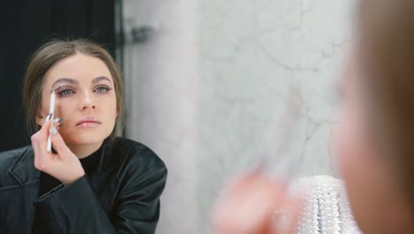 woman applying eye makeup in a mirror
