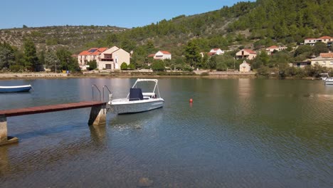 panning view of a very shallow cove with its numerous small traditional boats docked along long narrow piers along the shore of vela luka, croatia