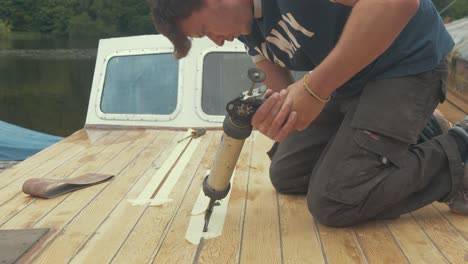 a young man applying sealant between wooden boat roof planks