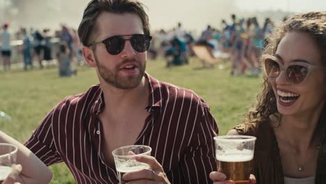 een groep vrienden die samen op het gras zitten op een muziekfestival en bier drinken terwijl ze praten.