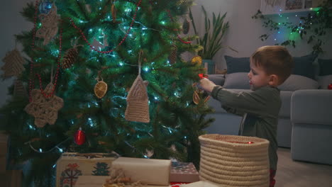 little boy decorating christmas tree on christmas eve wearing glass ball. high quality 4k footage