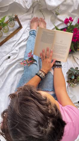 woman reading a book surrounded by plants and flowers