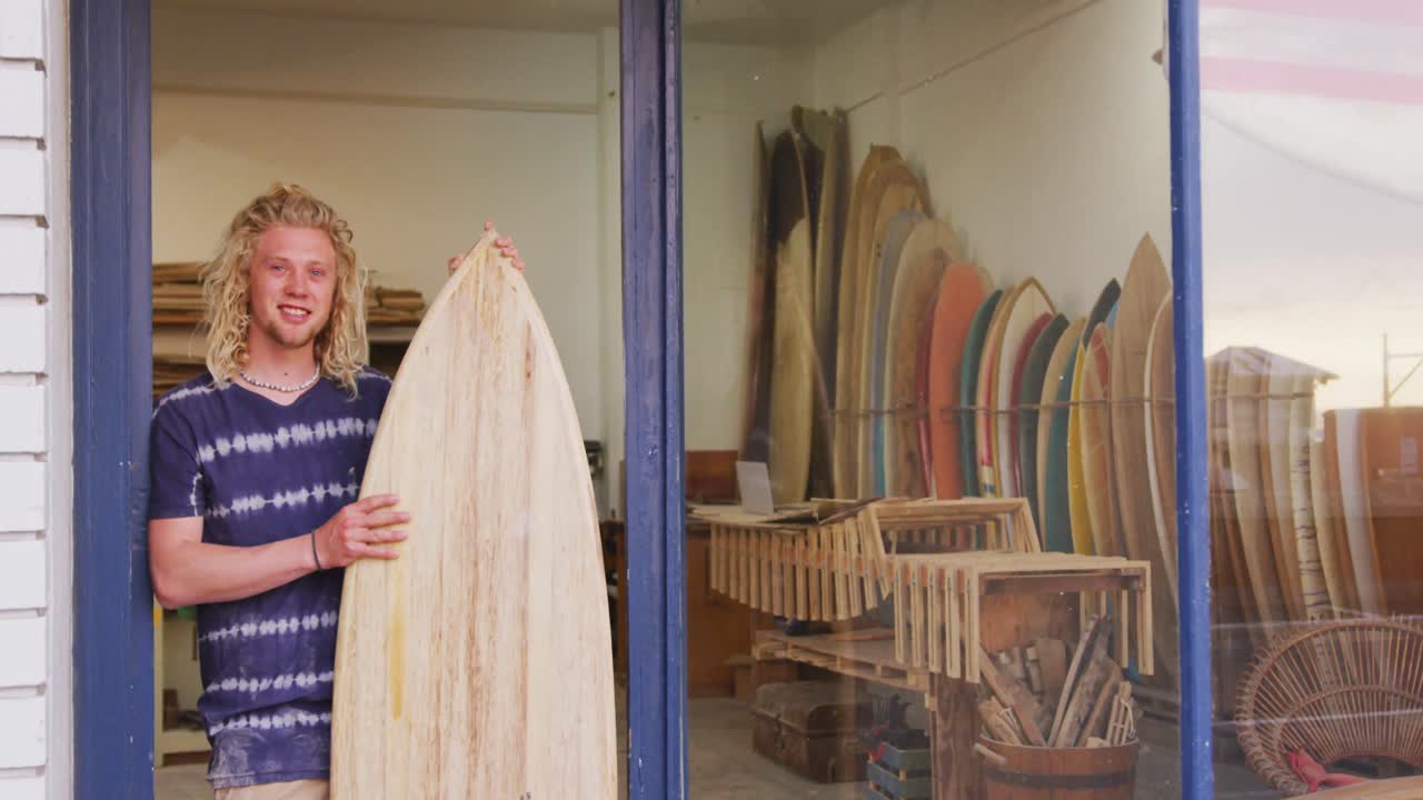 hombre caucásico fabricante de tablas de surf sosteniendo una tabla de surf nueva