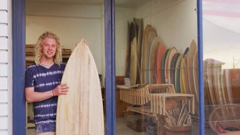 Caucasian-male-surfboard-maker-holding-a-brand-new-surfboard-