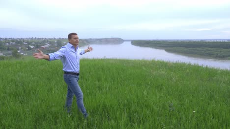 man enjoying the view of a river from a hill