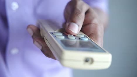 Person using air conditioner remote control