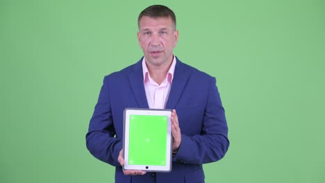 retrato de un musculoso y guapo hombre de negocios con traje contra el fondo verde del estudio