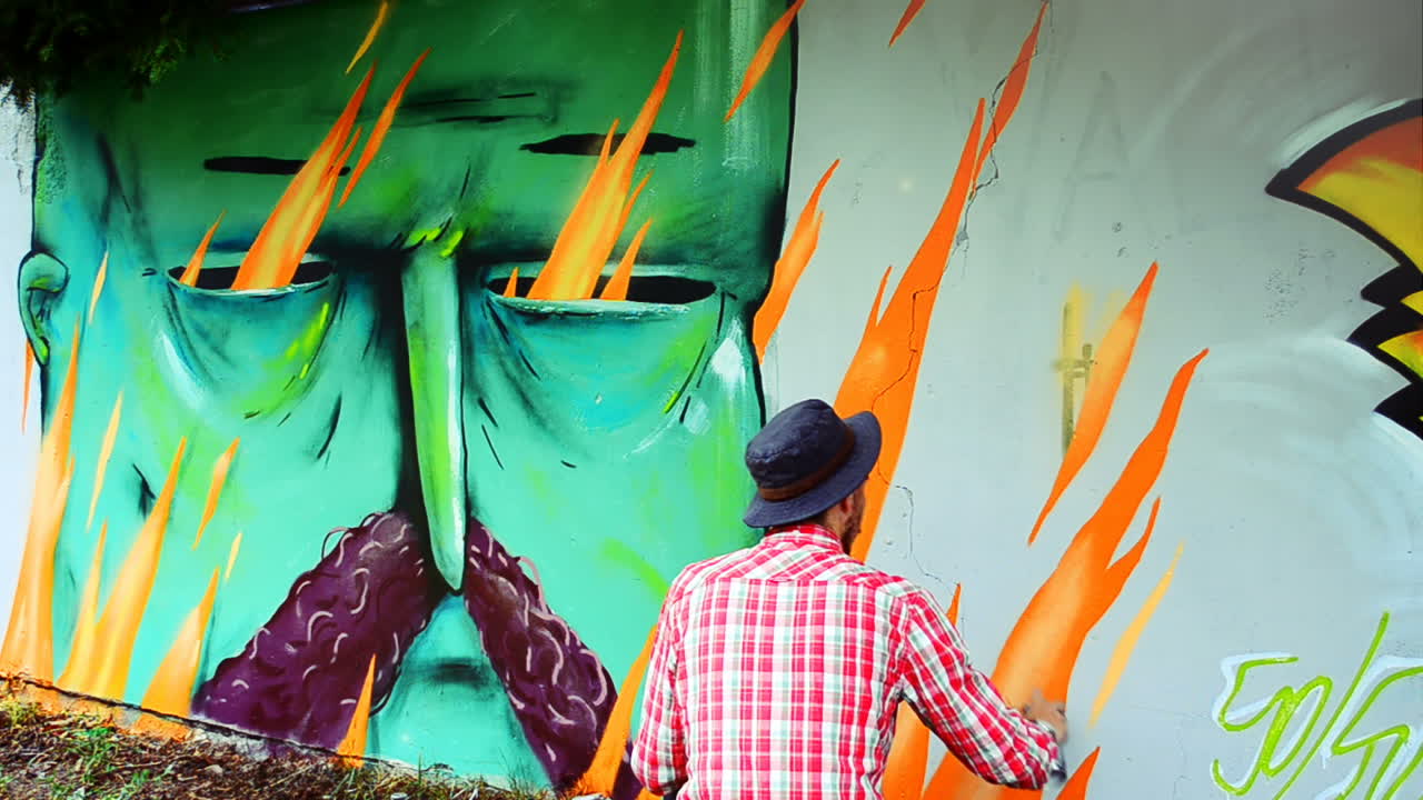 L'artista realizza graffiti su una recinzione. Disegno astratto