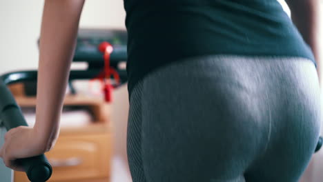 woman in leggings runs on treadmill in room close booty view