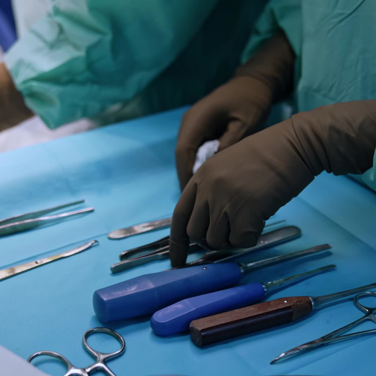 Chisels, forceps and mallet prepared for the orthopedic surgery. Close up. Hands of nurse wearing latex gloves are above the medical tools