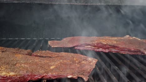 tiro deslizante de pechuga de ombligo de ternera sazonada cocinando en la parrilla del ahumador de carne
