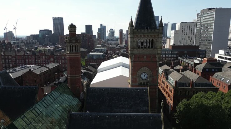 Ripresa aerea con drone attorno al tetto della Manchester Crown Court, mostrando uno skyline di grattacieli sullo sfondo
