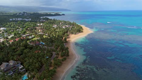 playa las ballenas with golden sands, turquoise waters, and tropical greenery, perfect for travel promotions or nature documentaries, dominican republic. aerial backward