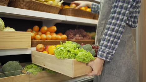 grocery store employee holding wooden crate with produce