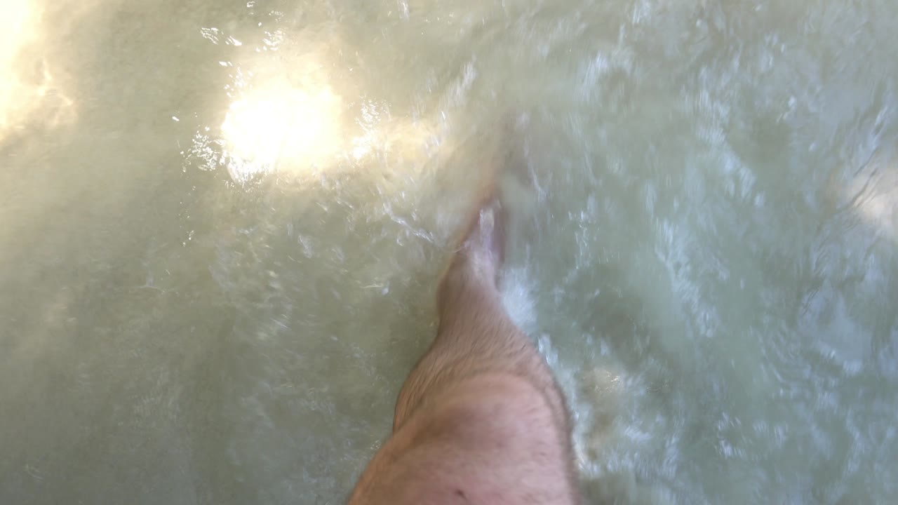 한 남자가  모래와 파도가 있는 해변을 따라 고 있다