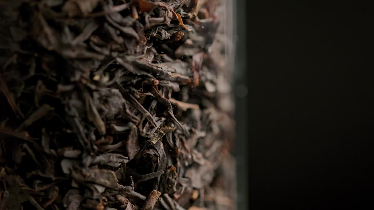 té negro seco giratorio en bucle dentro de la columna de vidrio fondo de primer plano