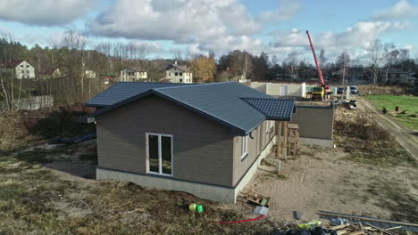 aerial zoom-out shot of a residential construction site with a new house and crane