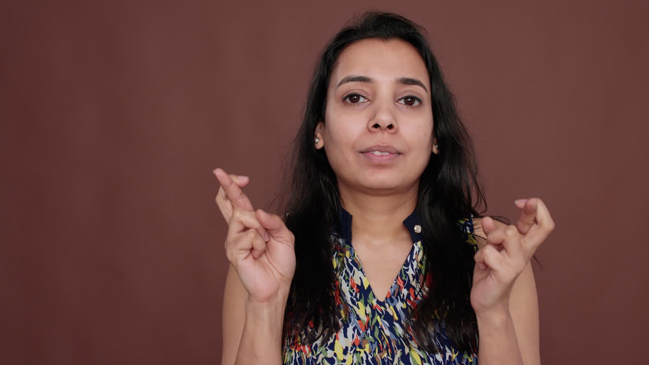 Indian woman holding fingers crossed for good luck in studio