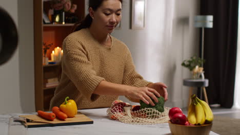 mujer volviendo a casa de las compras de comida desempaquetando una bolsa de verduras frescas en el mostrador en la cocina