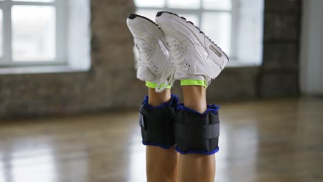 unrecognizable woman doing stretching exercise with ankle weights, close up