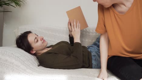 dos chicas están acostadas en el sofá y besándose