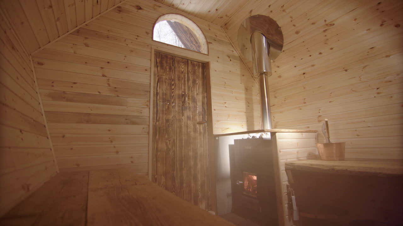Interior of empty steamy wooden sauna with lit wood-fired stove and rocks