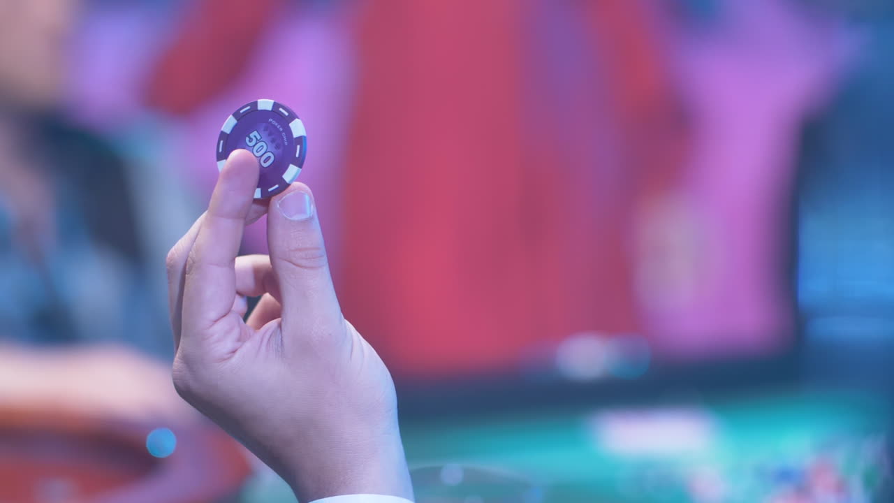 Giocatore di poker che fa girare una fiche da casinò nella mano.
