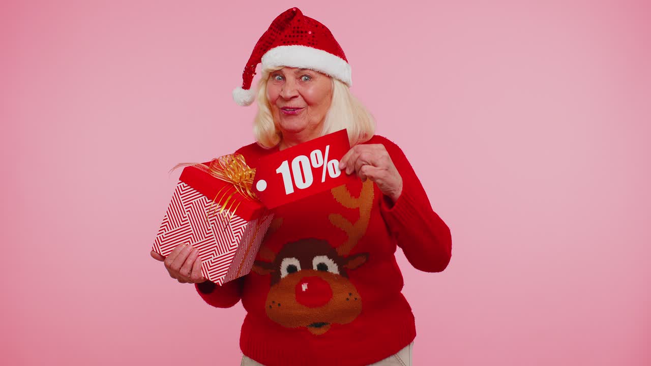 크리스마스 스웨터를 입은 할머니가 선물 상자와 10% 할인 문자를 보여주는 배너 텍스트