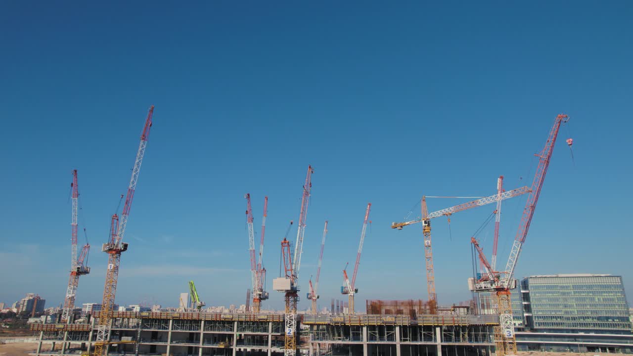Un edificio per uffici in costruzione con 11 gru, ripresa panoramica verticale con effetto parallasse.