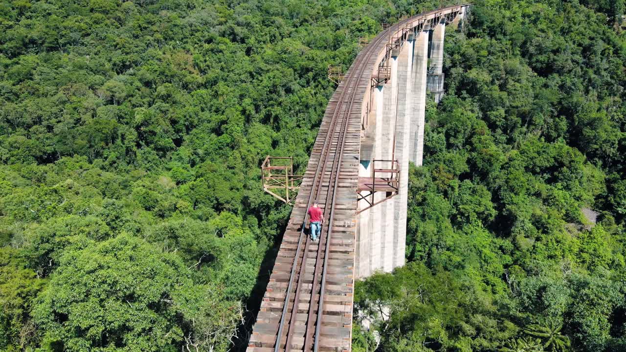 caminante solitario cruzando una enorme vía férrea a través de un valle