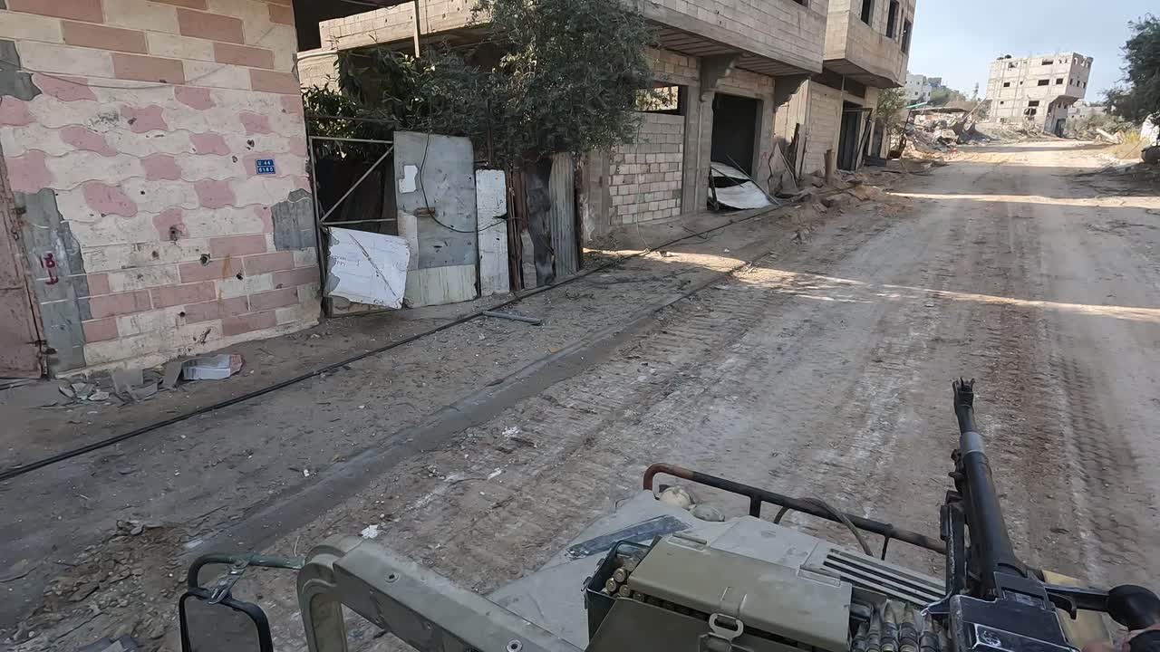 Striscia di Gaza — POV da un veicolo militare che si muove attraverso una strada residenziale danneggiata con edifici distrutti e detriti