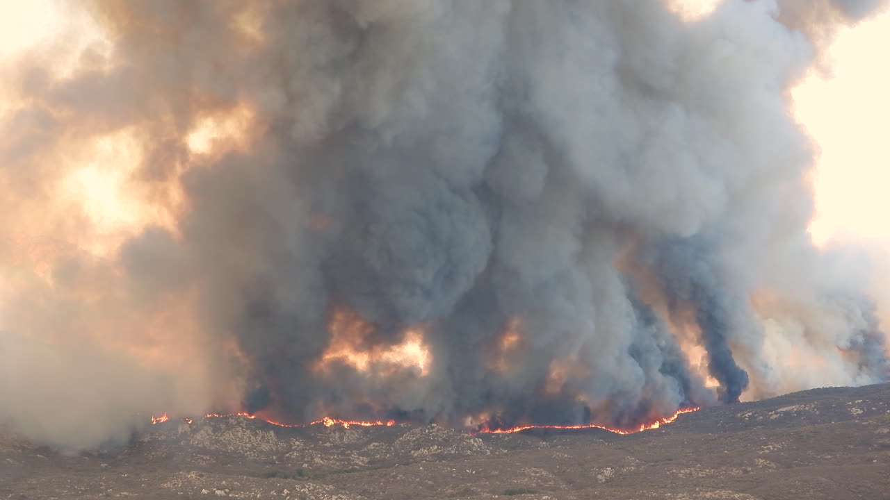 vista aérea del avión de extinción de incendios que vuela sobre incendios forestales en llamas con humo oscuro en california - contaminación ambiental durante el calor y el cambio climático