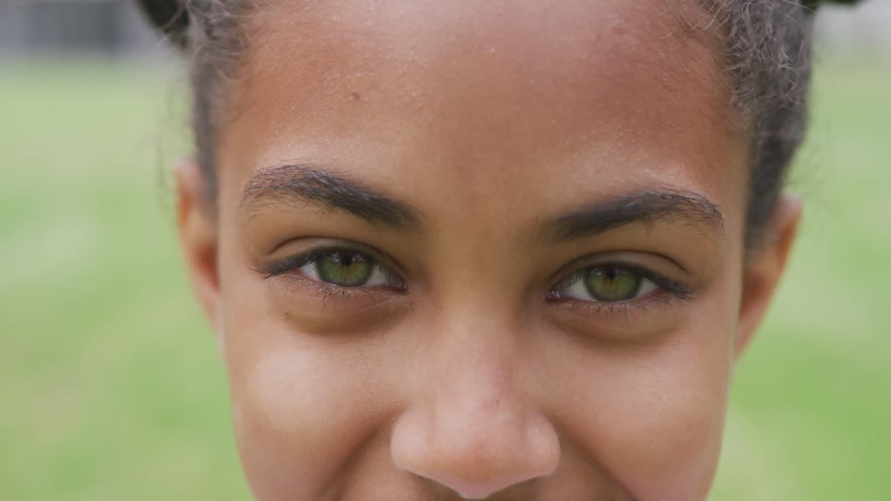 retrato de video de cerca de los ojos verdes de una estudiante biracial sonriente en el campo de juego