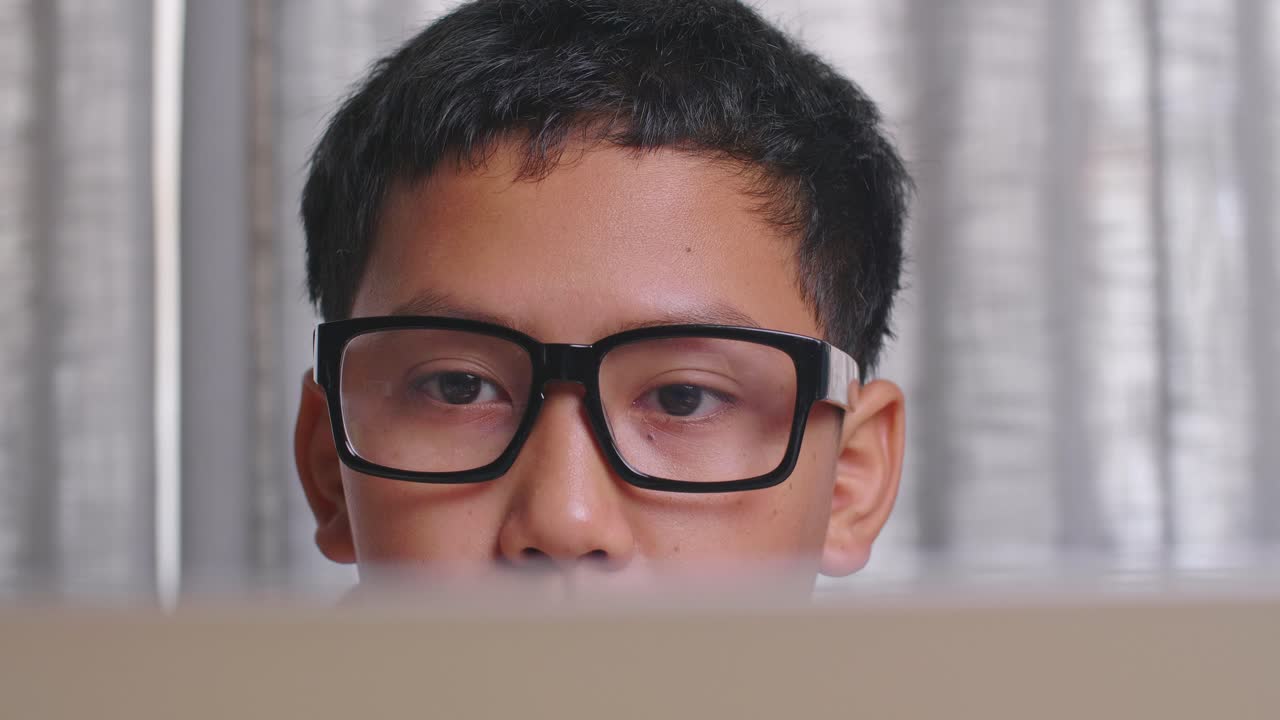Boy Wearing Glasses Looking at a Laptop
