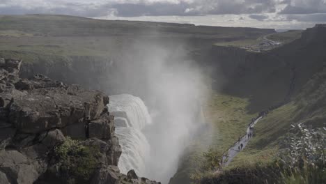 static shot of the gullfoss waterfall with tourists walking past in iceland