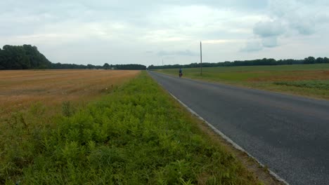 cyclist bikepacking on country road with flashing head safety light, rear view