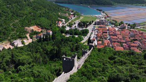 ston defensive walls with salt pans and town houses in the distance in croatia. - aerial shot