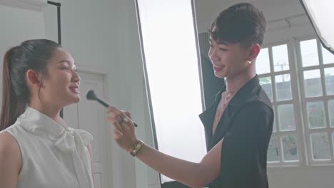 backstage of the photo shoot: make-up artist applies makeup on beautiful asian model