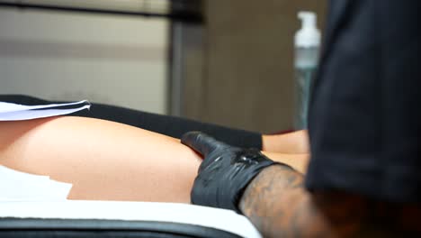 close-up view of a tattoo artist applying a tattoo to a client's leg