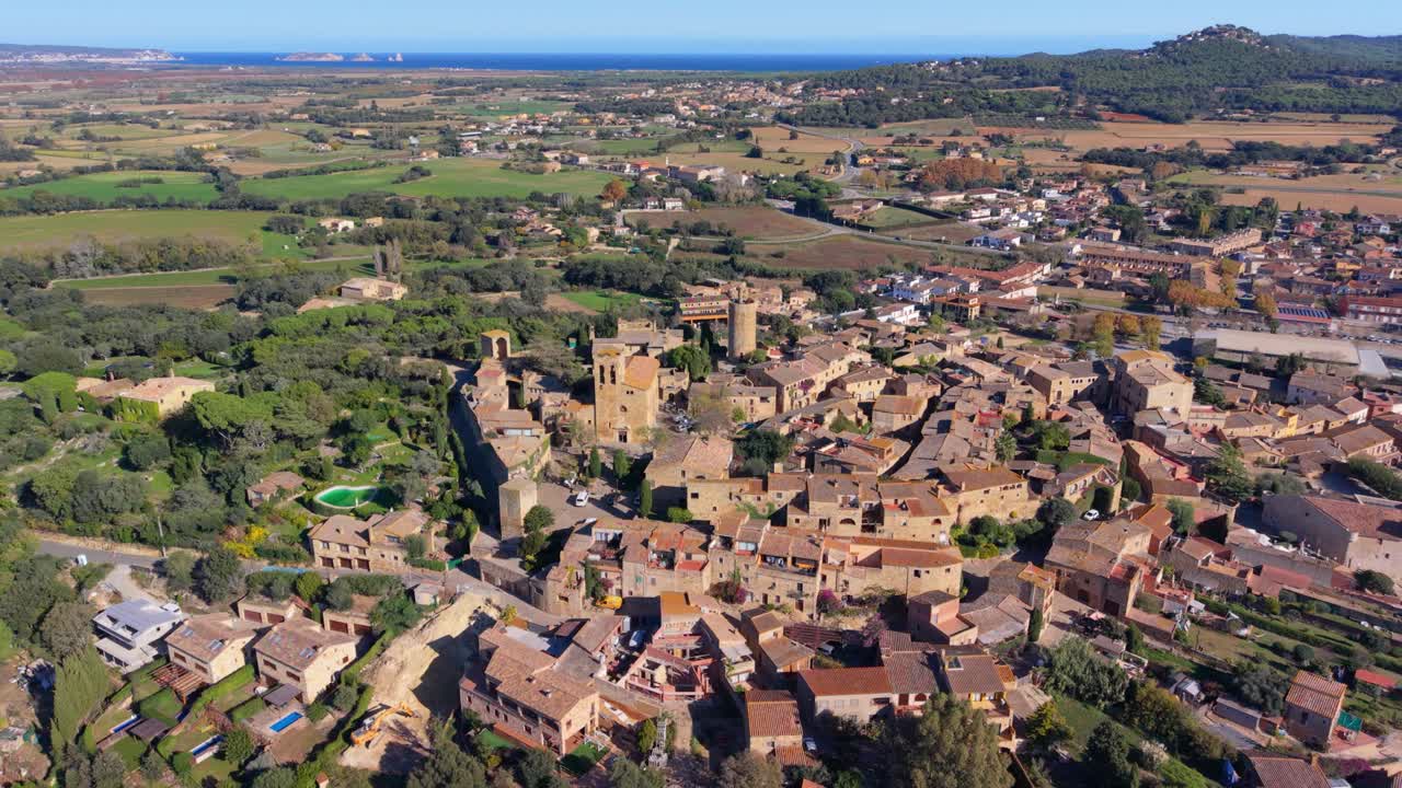 High altitude panoramic view showcasing the historic medieval village of pals in catalonia. Spain. Revealing its ancient stone architecture. Surrounding countryside. And the distant mediterranean sea