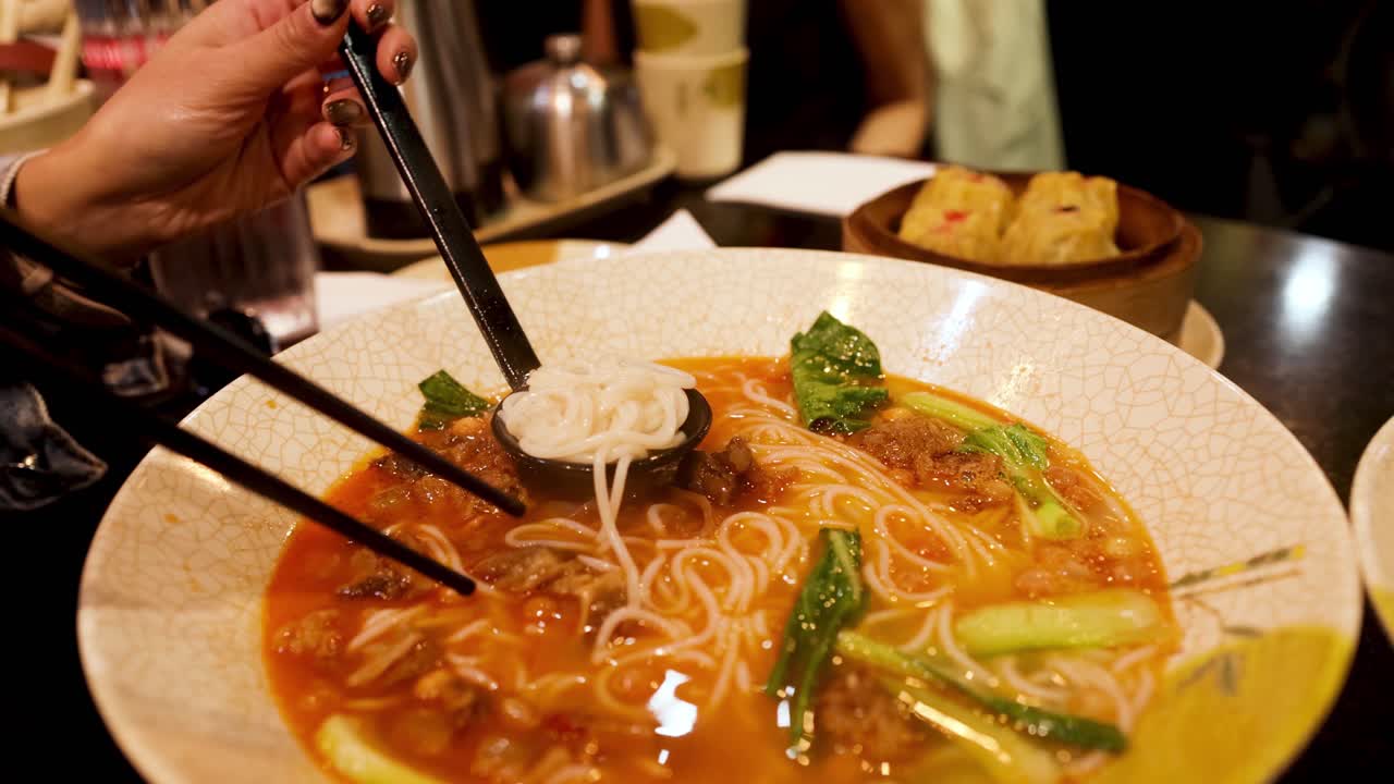 persona comiendo fideos con palillos en melbourne